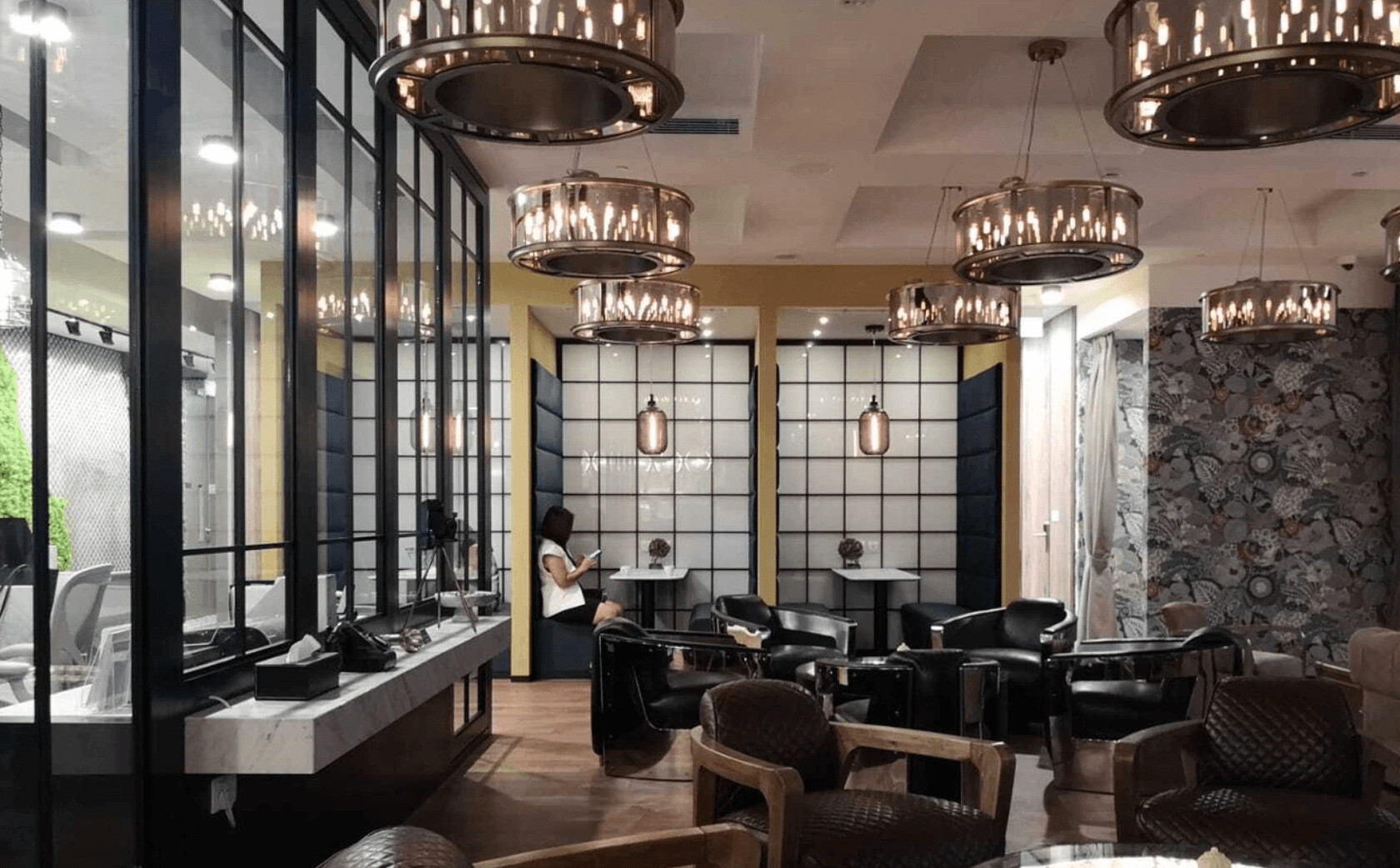 Elegant coworking lounge with vintage lighting, leather chairs, and private booth seating.